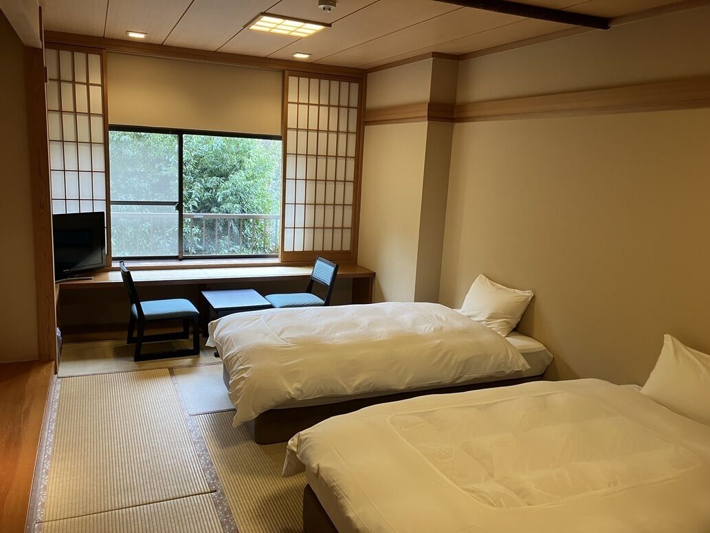 A hotel room with two beds, a desk, and a chair.