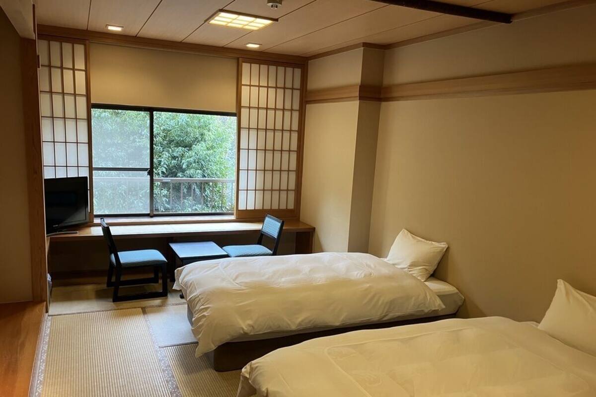 Une chambre d’hôtel avec deux lits, un bureau et une chaise.