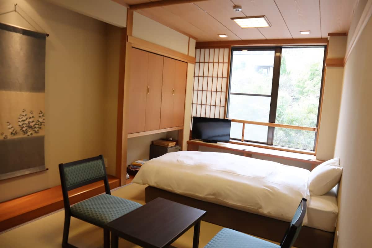 Une chambre d’hôtel avec un lit, une télévision, un bureau et une chaise.