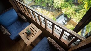 A balcony with a wooden railing, a small table with a plant, and blue cushioned seating. - Yukyo No Hibiki Yusai (Minamioguni)