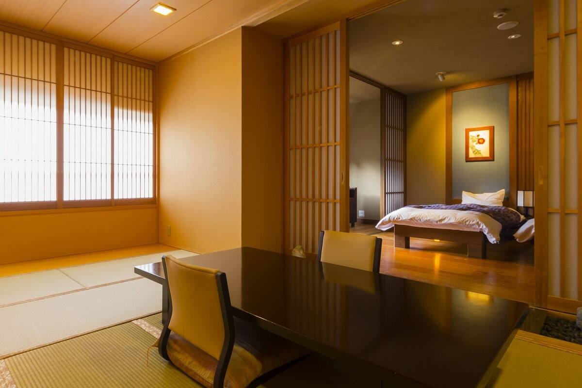 Une pièce de style japonais traditionnel, avec un sol recouvert de tatamis, une table basse et un lit équipé d’un futon.