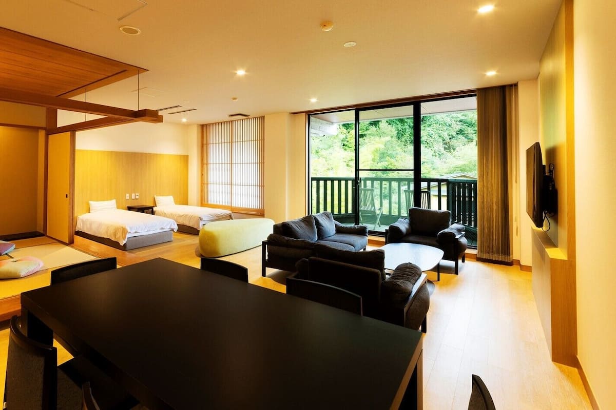 Une chambre d’hôtel moderne comprenant un coin repas, deux lits, un ensemble de canapés et un téléviseur.