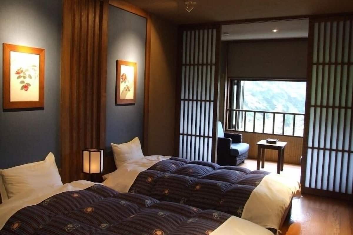 Une chambre d’hôtel avec deux lits, une petite table, une chaise et une vue sur l’extérieur.