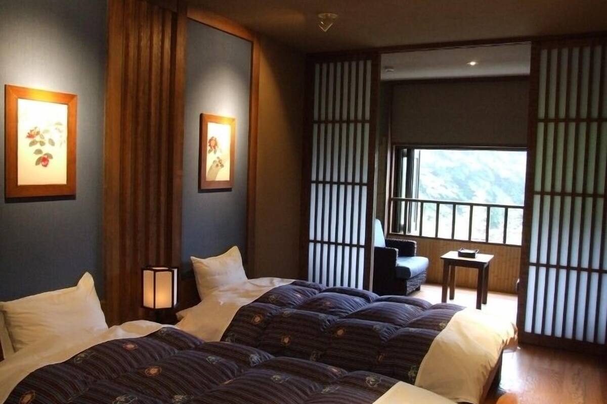 Une chambre d’hôtel avec deux lits, une petite table, une chaise et une vue sur l’extérieur.