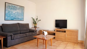 A living room with a sofa, a coffee table, a TV, and a cabinet. - Sagitario Villas (Ciutadella de Menorca)