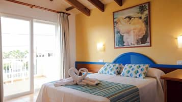 A hotel room with a bed, a painting, and a view of the outside.