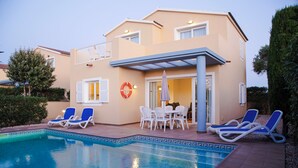 A two-story building with a swimming pool, outdoor seating, and a lifebuoy on the wall. - Sagitario Villas (Ciutadella de Menorca)