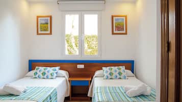A double room with two beds, a wooden headboard, a window with blinds, and two framed pictures on the walls.