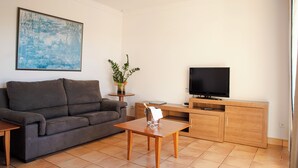 A living room with a sofa, a coffee table, a TV, and a cabinet. - Sagitario Villas (Ciutadella de Menorca)
