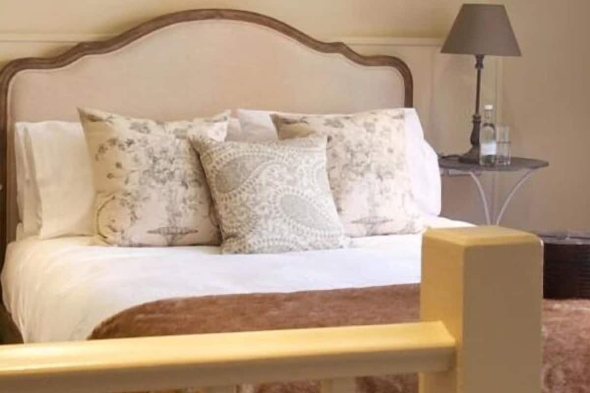 A bed with a wooden headboard, patterned pillows, and a bedside table with a lamp.