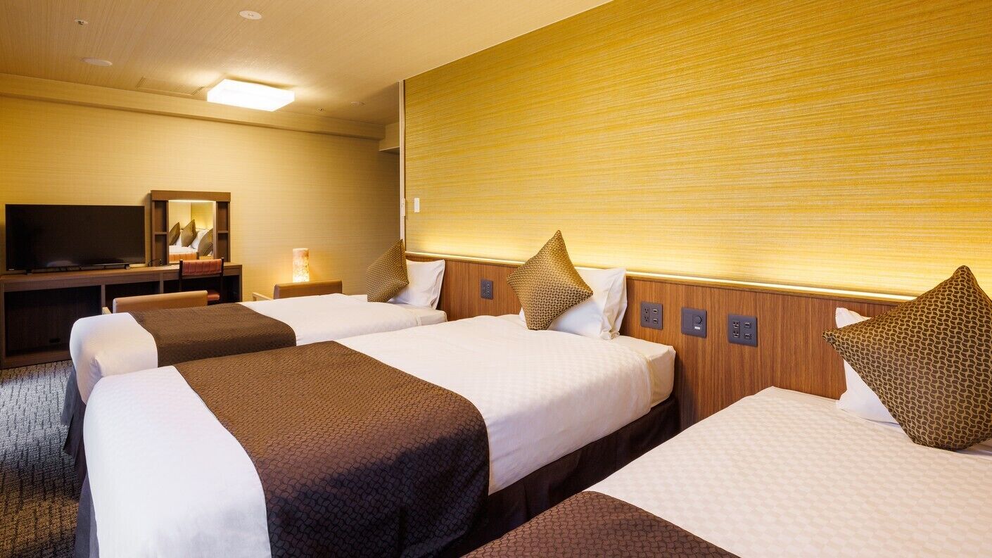 Ein Hotelzimmer mit zwei Betten, einem Fernseher und einem hölzernen Kopfteil.