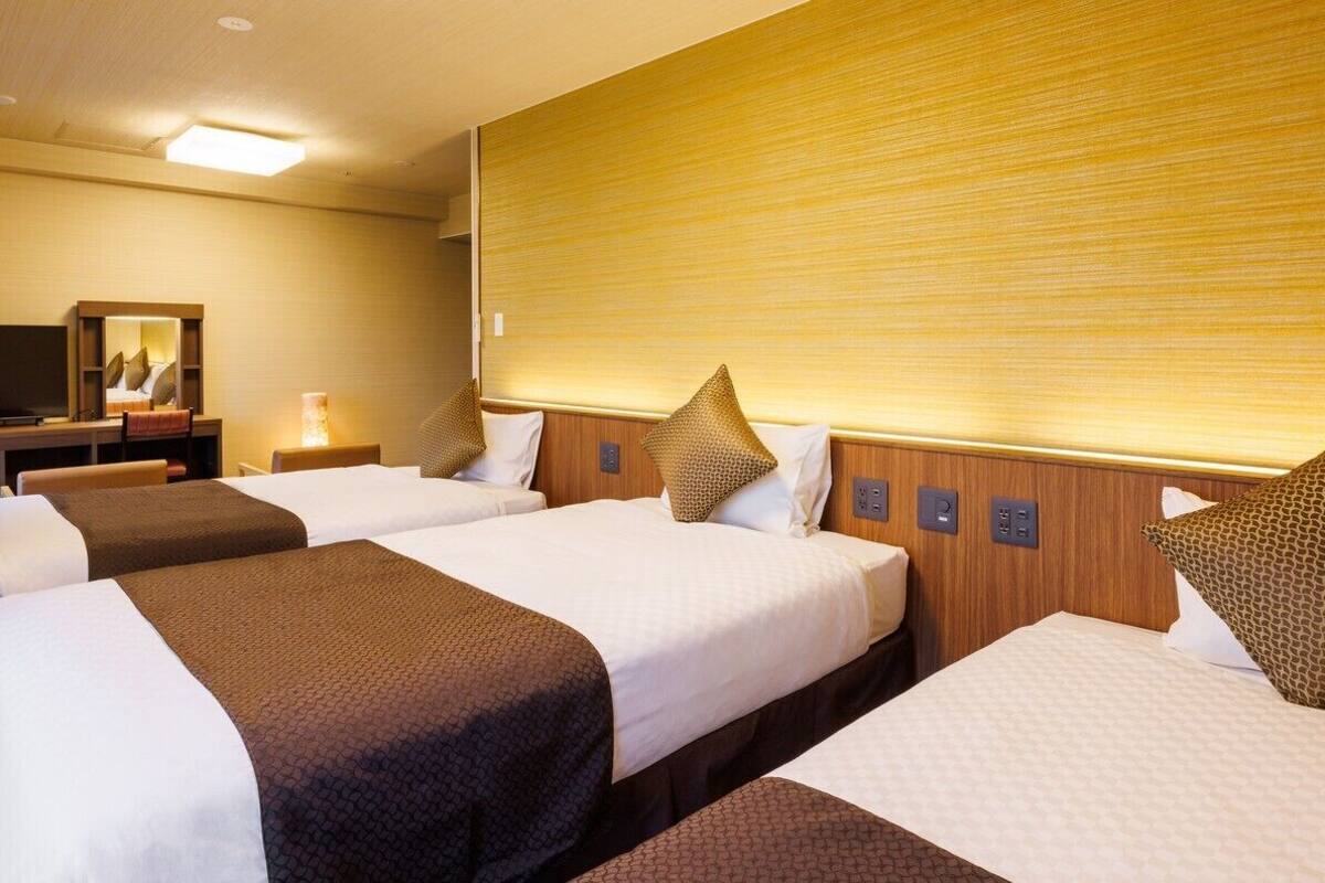 Ein Hotelzimmer mit zwei Betten, einem Fernseher und einem hölzernen Kopfteil.