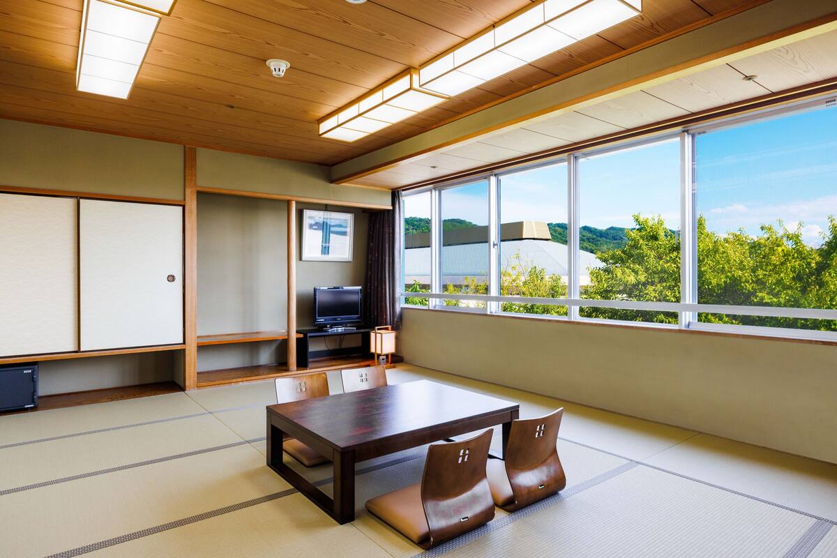 A traditional Japanese-style room with tatami flooring, a low table, and a television.