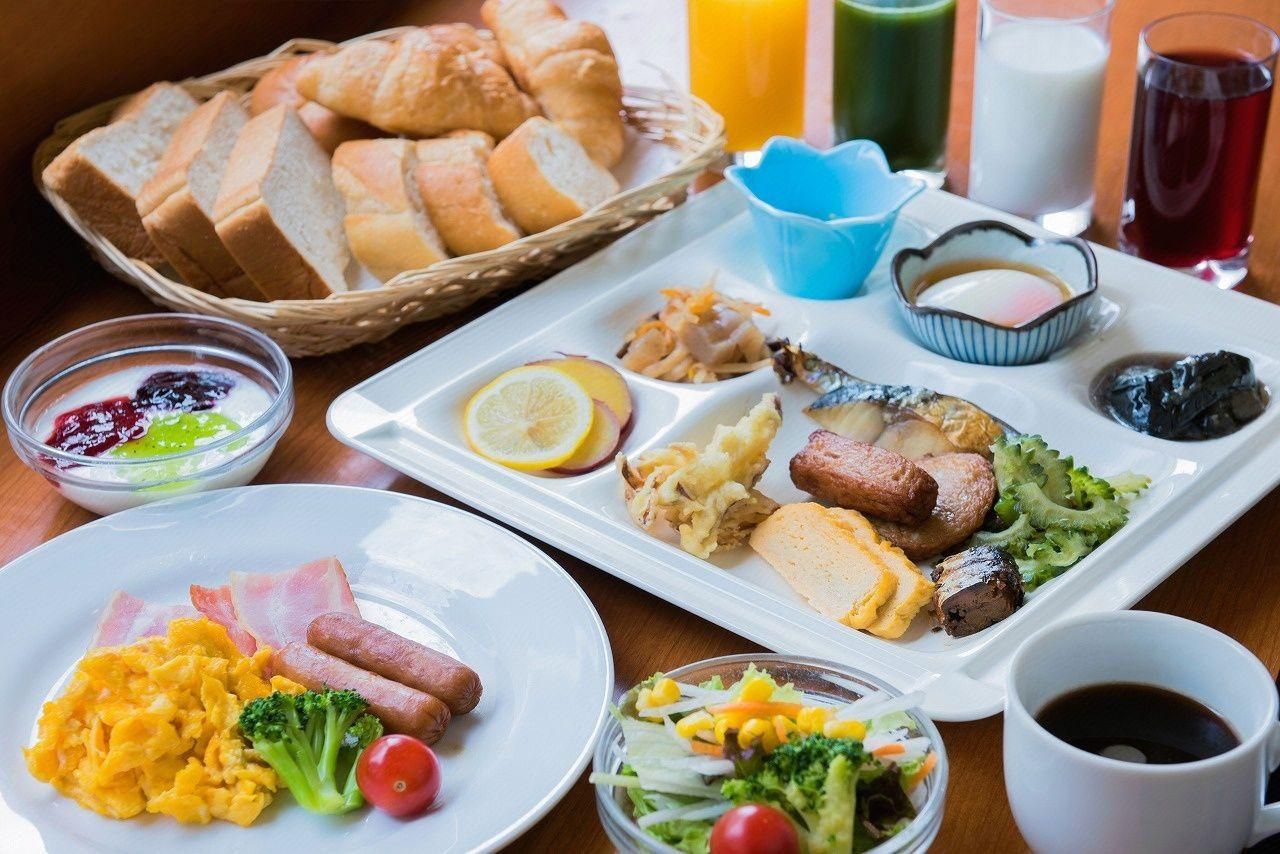 A breakfast buffet with various dishes, including eggs, bacon, sausages, and vegetables.
