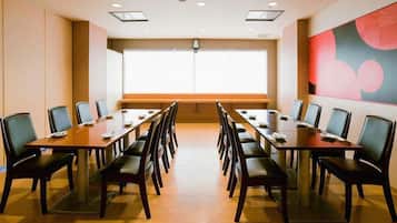 A conference room with a long table and chairs, a large window, and a modern abstract painting on the wall.