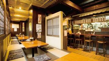 A traditional Japanese restaurant interior with tatami mats, wooden tables, and a counter with stools.