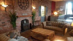 A cozy living room with a brick fireplace, plush sofas, and a wooden coffee table. - Herdwicks (Millom)