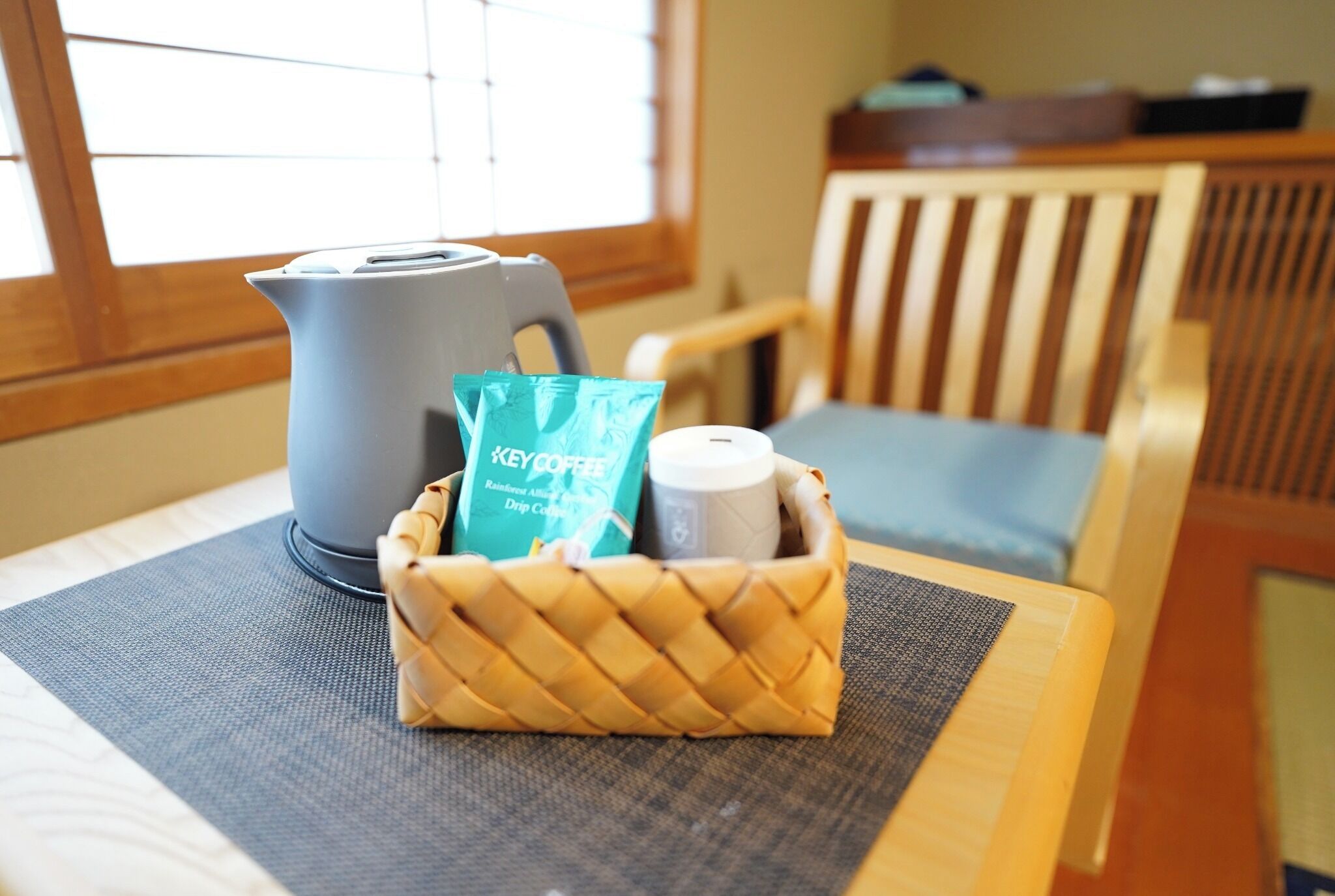 Une machine à café, un paquet de café et une bouteille sont posés sur une table, à côté d’un panier en osier.