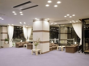 Un hall d’hôtel comprenant un espace salon, un comptoir d’accueil et une grande fenêtre.