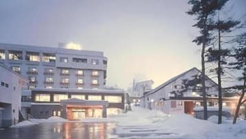 Um hotel com vários andares, área de estacionamento e terreno coberto de neve.