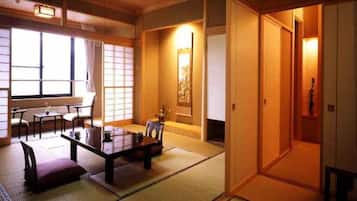 A traditional Japanese room with tatami flooring, a low table with cushions, and sliding doors.