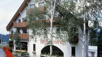A multi-story building with a white facade, a wooden balcony, and a sign that reads 'put endrer'.