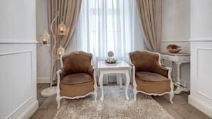 Una habitació amb dues cadires marrons tapissades, una taula blanca amb un objecte decoratiu i una làmpada de peu blanca amb una espelma.