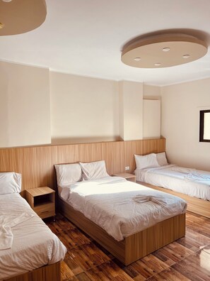 Hotellihuone, jossa on kaksi sänkyä, puulattia ja moderni kattorakenne.