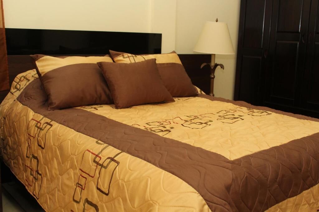 Una cama bien hecha con un edredón estampado y varias almohadas.