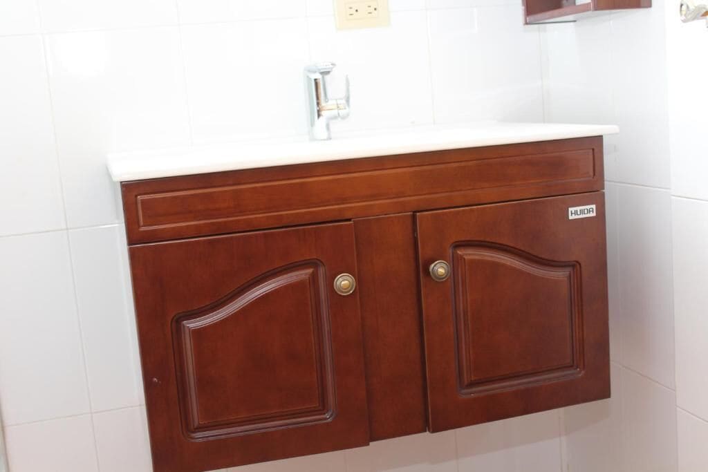 Une coiffeuse en bois avec un plan de travail blanc et un seul robinet.