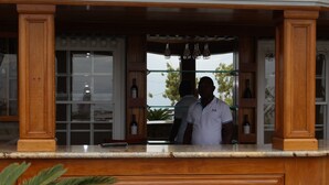 A bar area with wooden paneling, a counter, and shelves with bottles.