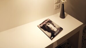 A white table with a magazine, a vase with flowers, and a hanging light fixture. - Re Ruggero Rooms (Reggio Calabria)