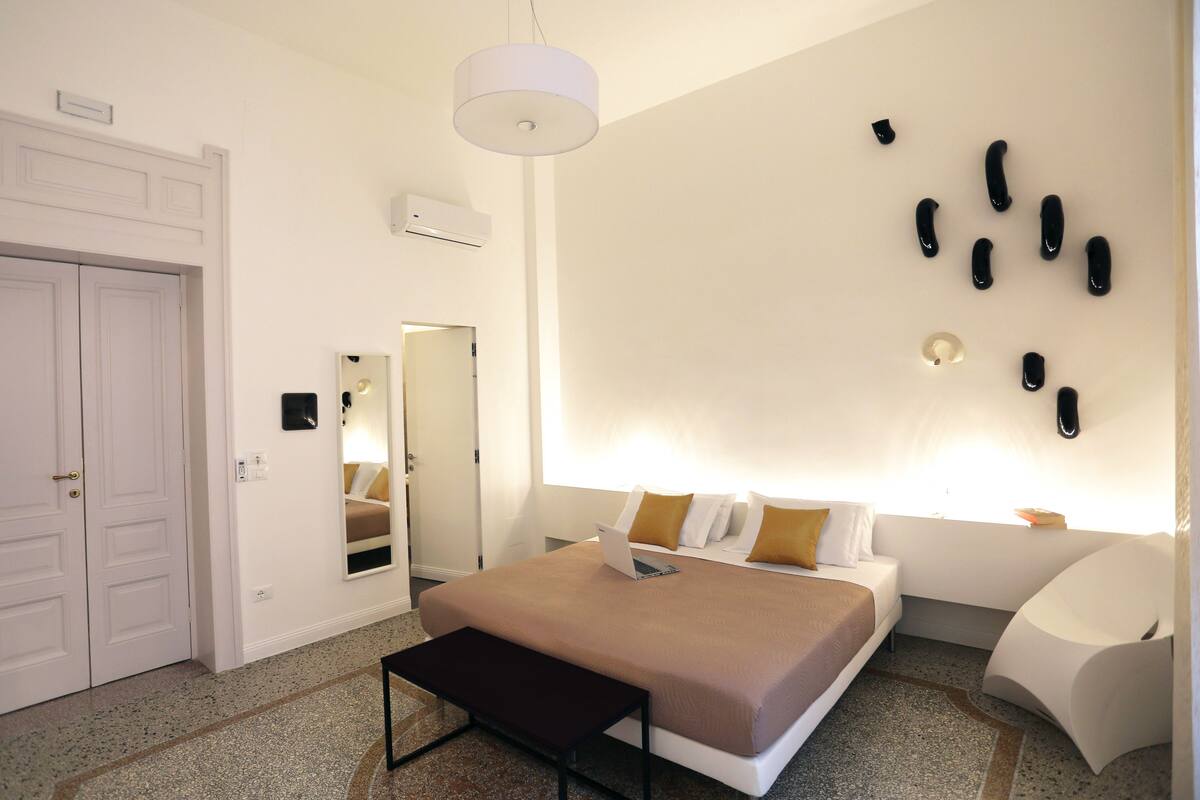 A modern bedroom with a bed, bedside table, and a unique wall art piece.