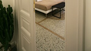 A bedroom with a bed, a bedside table, a hanging light fixture, and a wall with abstract art. - Re Ruggero Rooms (Reggio Calabria)