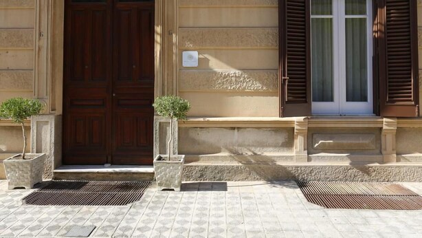 A building facade with a large wooden door, a window with shutters, and two potted plants. - Re Ruggero Rooms (Reggio Calabria)