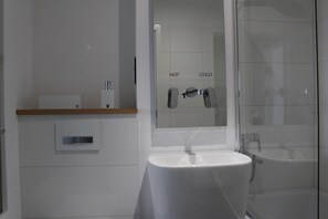 A modern bathroom with a white sink, a mirror, and a glass shower enclosure. - Luxury holiday apartment Tegernsee - Design Ferienappartement Tegernsee (Tegernsee)