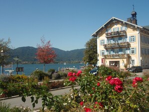 A hotel with a balcony overlooking a lake, surrounded by lush gardens and a clear sky. - Luxury holiday apartment Tegernsee - Design Ferienappartement Tegernsee (Tegernsee)
