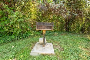 A bench with a signpost in a grassy area surrounded by dense foliage.