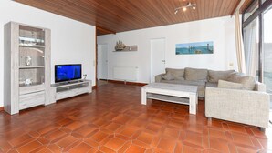 A living room with a wooden ceiling, a television, a sofa, and a coffee table. - Holiday house in Taddigshörn 303 - holiday houses beach castles (Esens)