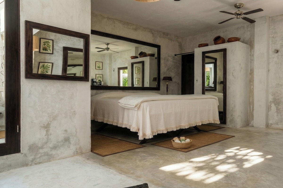 A bedroom with a bed, a ceiling fan, and a large mirror.