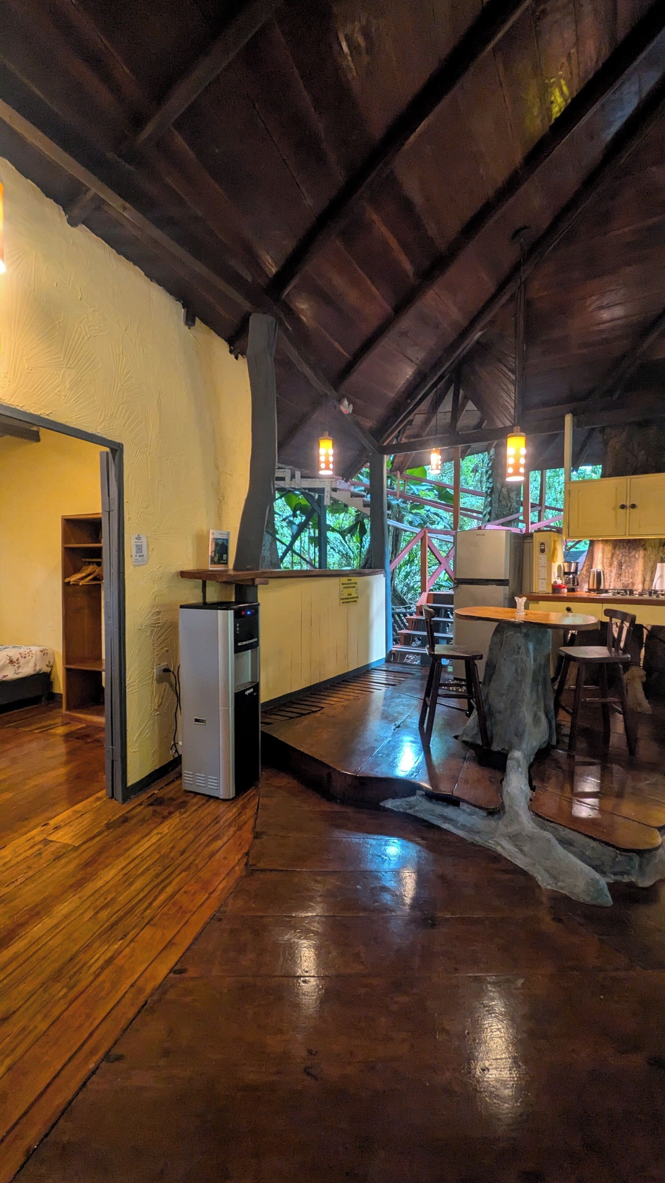 A rustic kitchen with wooden floors, a refrigerator, and a dining area with chairs and a table.