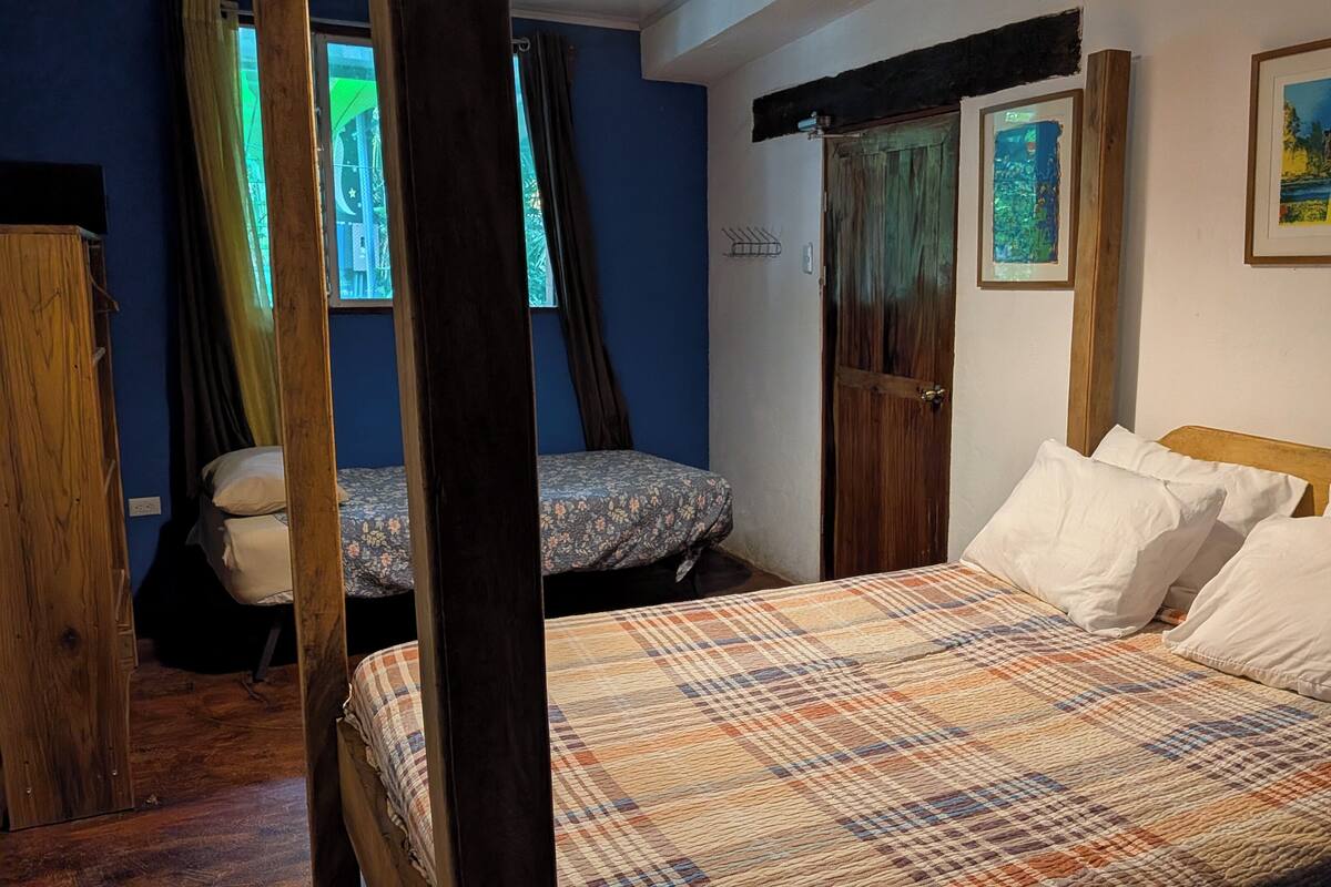 Een slaapkamer met een bed, een kledingkast, een raam met gordijnen en een deur.