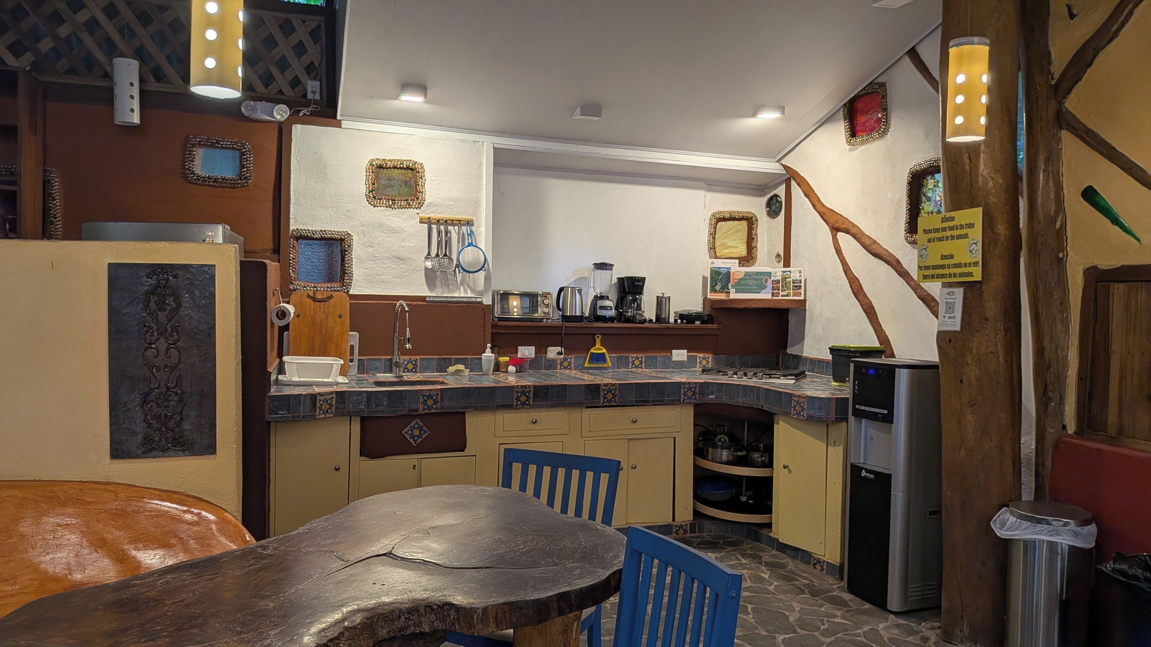 A kitchen with a stone countertop, a sink, and a stove. There are cabinets and a trash can visible.