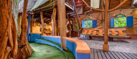 A treehouse with a spiral staircase, wooden beams, and a cozy seating area with cushions.