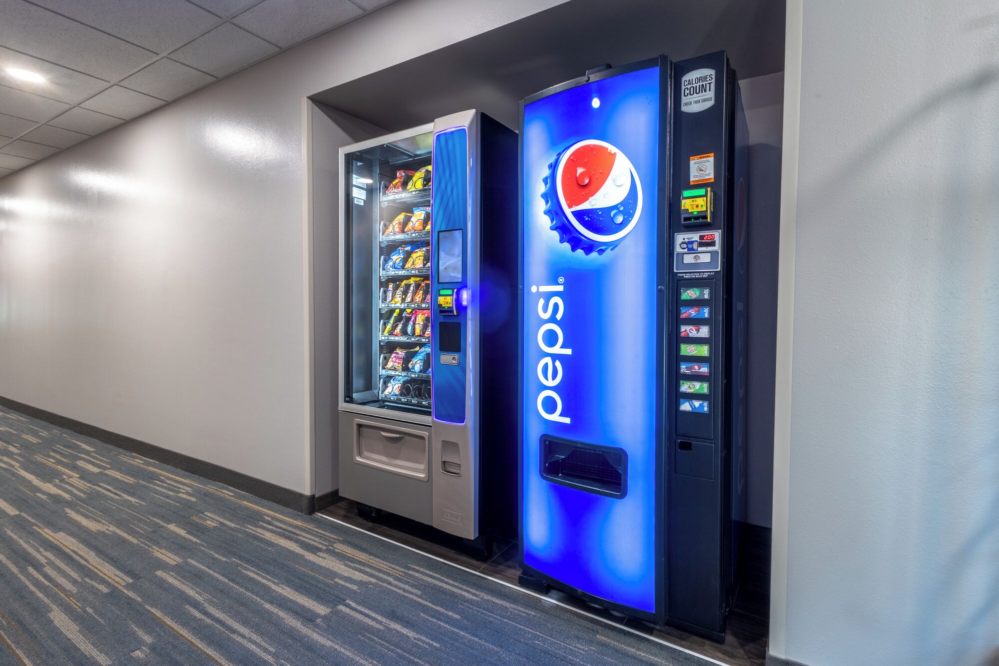 A hallway with two vending machines, one for Pepsi and another for snacks.