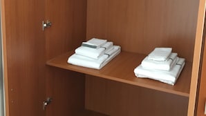 Un armari de fusta amb dues prestatgeries plena de tovalloles blanques plegades.