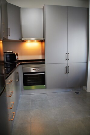 Una cocina moderna con electrodomésticos de acero inoxidable, armarios grises y un horno empotrado.