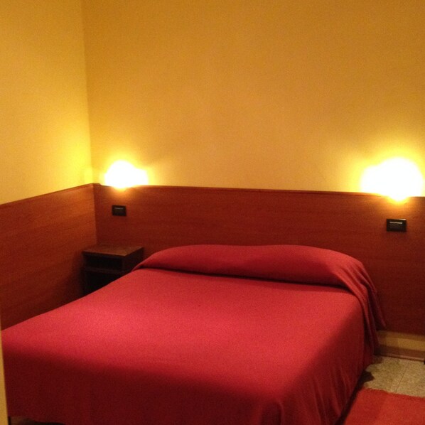 A single bed with a red bedspread in a room with wooden headboard and nightstands. - Albergo Parigi (Genoa)