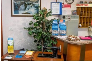 Ein Empfangsbereich mit einer Vintage-Nähmaschine, einer Pflanze, Broschüren und einer Wanduhr.