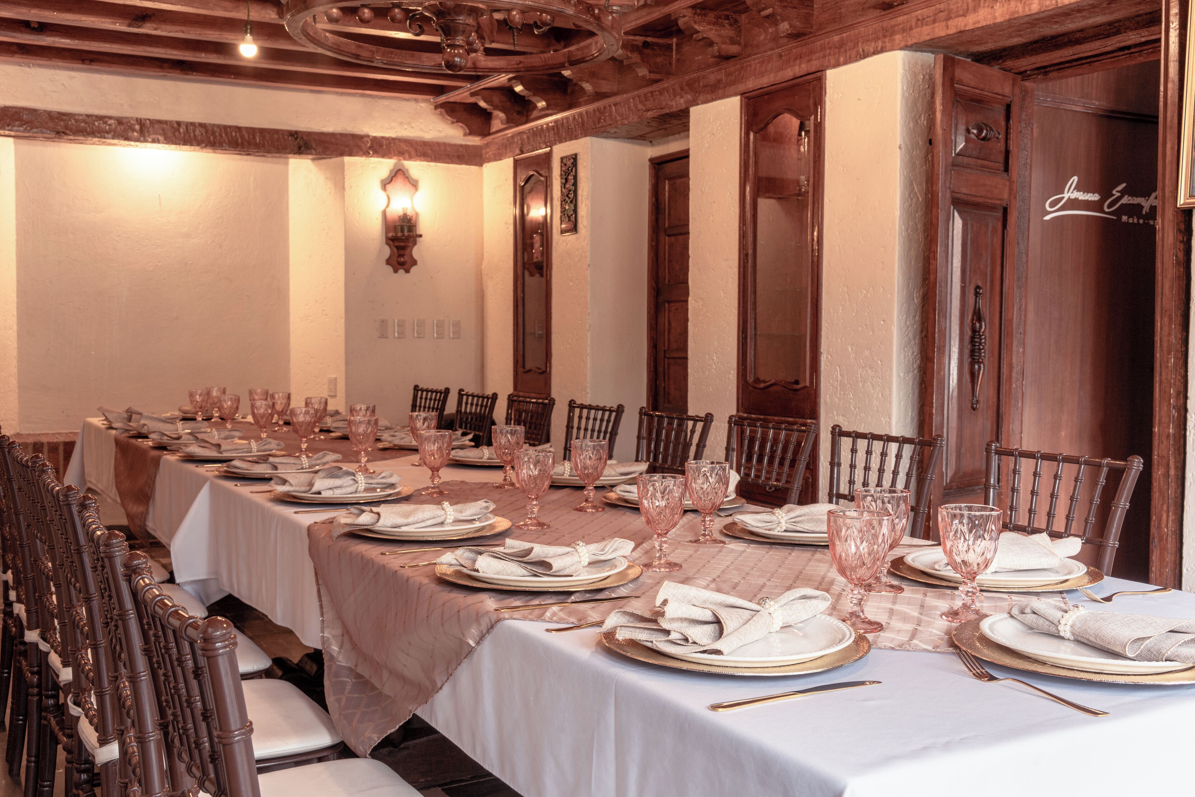 Une longue table à manger, dressée pour un repas formel, avec de nombreuses chaises, des nappes blanches et de beaux verres.